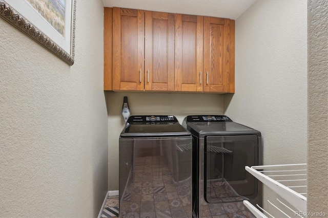 laundry area featuring cabinet space, separate washer and dryer, and a textured wall