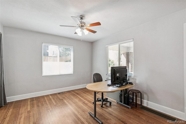 office area with a textured ceiling, a wealth of natural light, hardwood / wood-style floors, and ceiling fan