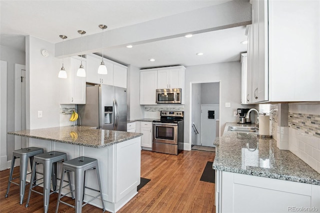 kitchen with light wood-type flooring, appliances with stainless steel finishes, white cabinetry, stone countertops, and sink