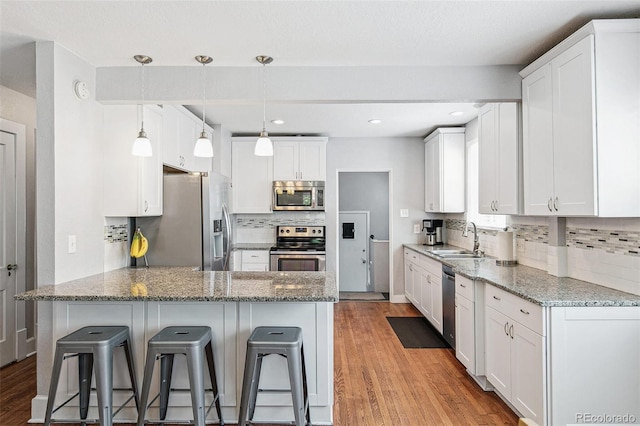 kitchen featuring light wood-type flooring, stainless steel appliances, sink, and a breakfast bar