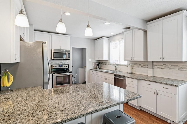 kitchen with white cabinets, light hardwood / wood-style flooring, stainless steel appliances, sink, and a kitchen breakfast bar