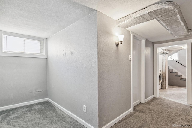 hall featuring washer / clothes dryer, carpet flooring, and a textured ceiling