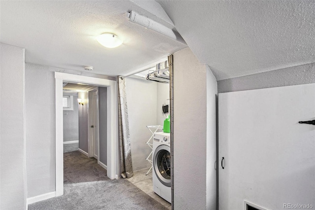 clothes washing area featuring a textured ceiling, washer / dryer, and light carpet