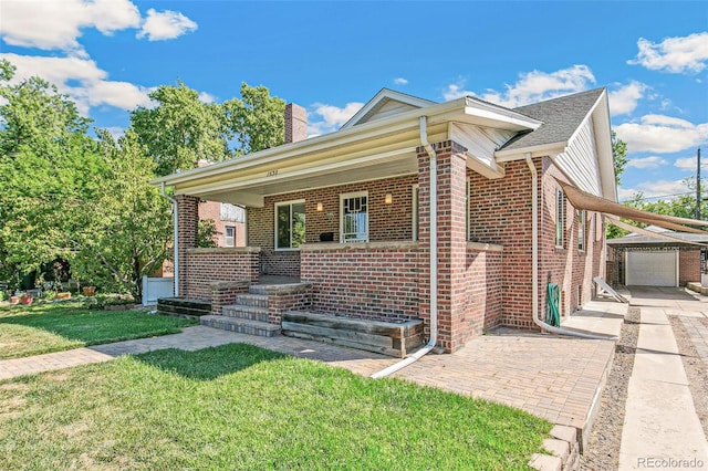 view of front of property featuring a garage, a front yard, covered porch, and an outbuilding