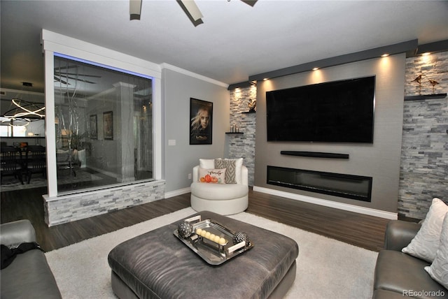 living room with ornamental molding, dark wood-type flooring, and ceiling fan