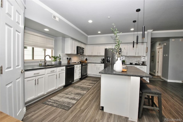 kitchen featuring pendant lighting, a breakfast bar, white cabinetry, a center island, and black appliances