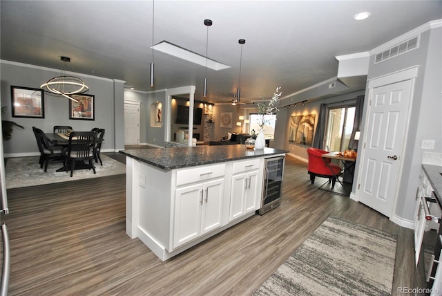 kitchen with white cabinets, a kitchen island, pendant lighting, and wine cooler