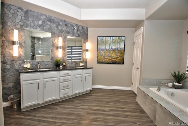 bathroom featuring vanity, tiled bath, and hardwood / wood-style floors