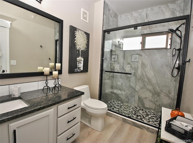 bathroom featuring vanity, toilet, a shower with shower door, and wood-type flooring