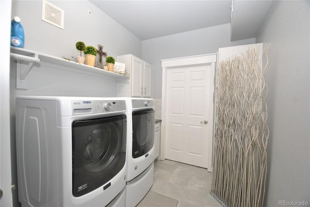 clothes washing area with cabinets and washing machine and clothes dryer