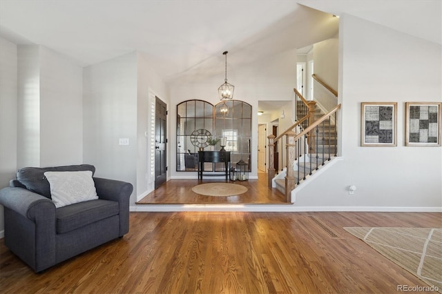 entrance foyer featuring hardwood / wood-style flooring, high vaulted ceiling, and a notable chandelier