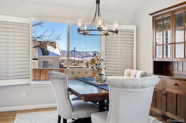 dining space with a mountain view, vaulted ceiling, light hardwood / wood-style flooring, and a notable chandelier