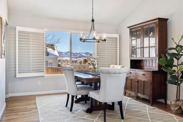 dining space with a mountain view, light hardwood / wood-style flooring, a chandelier, and lofted ceiling