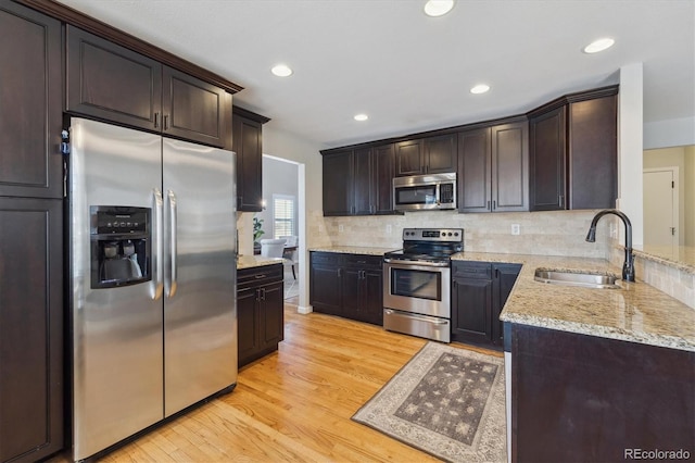 kitchen featuring dark brown cabinetry, sink, light hardwood / wood-style floors, and appliances with stainless steel finishes