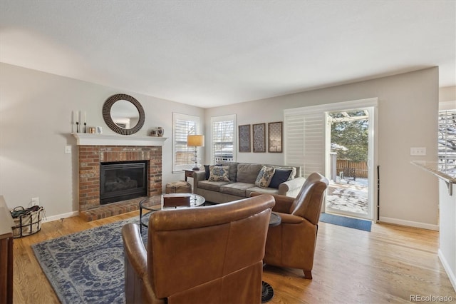 living room with plenty of natural light, light hardwood / wood-style floors, and a brick fireplace