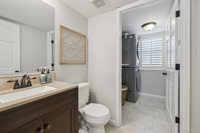 bathroom featuring vanity, stacked washing maching and dryer, and toilet