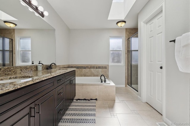 bathroom with tile patterned flooring, shower with separate bathtub, vanity, and a skylight