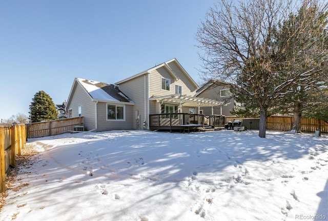 snow covered back of property with a pergola and a deck