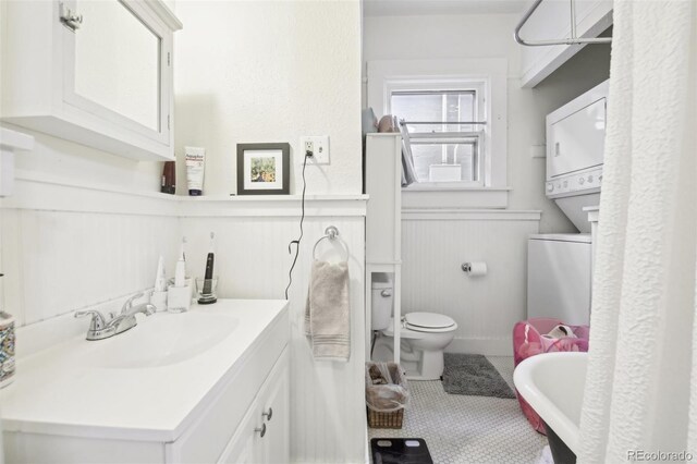 bathroom featuring tile patterned floors, toilet, vanity, and stacked washing maching and dryer