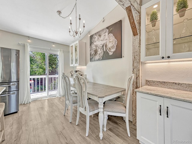 dining room with vaulted ceiling with beams, light hardwood / wood-style flooring, and a chandelier