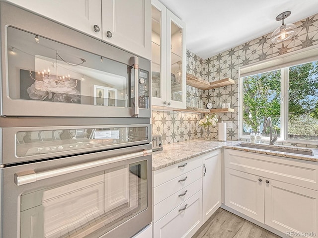 kitchen with white cabinetry, sink, backsplash, appliances with stainless steel finishes, and light wood-type flooring