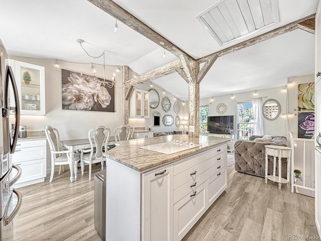 kitchen featuring white cabinets, a center island, light stone counters, and light wood-type flooring