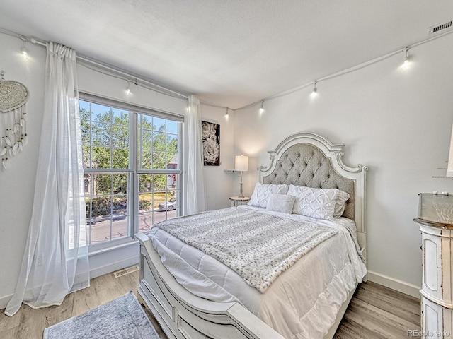 bedroom featuring track lighting, a textured ceiling, and hardwood / wood-style flooring