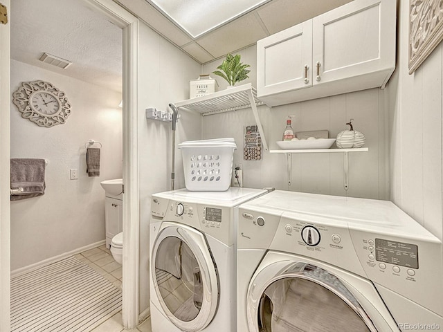 laundry room featuring cabinets, light tile patterned flooring, and washing machine and dryer