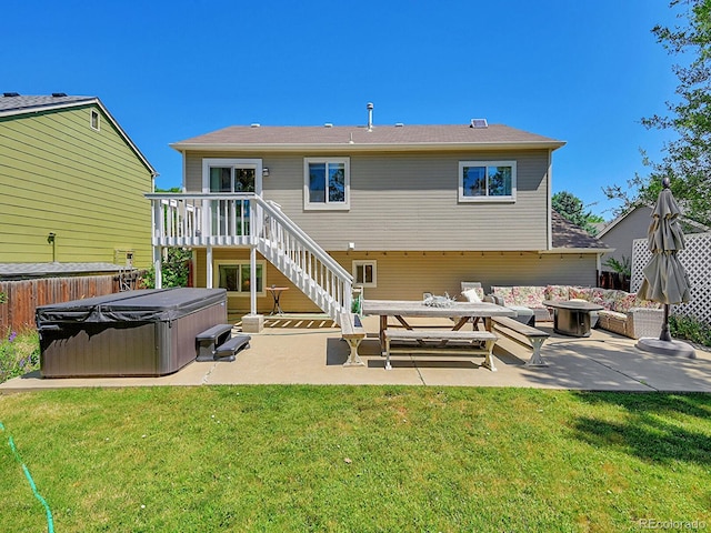 back of house with a hot tub, a wooden deck, a patio area, and a lawn