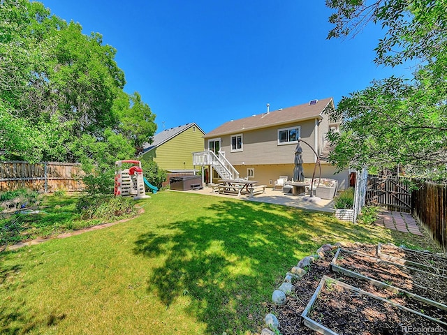 rear view of property with a lawn, a patio area, and a hot tub