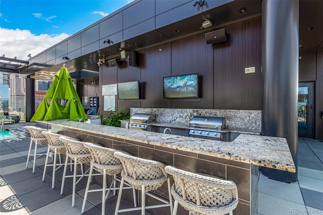 view of patio featuring exterior bar and a grill