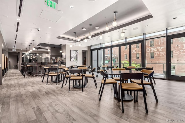 dining space featuring hardwood / wood-style flooring, plenty of natural light, and a raised ceiling