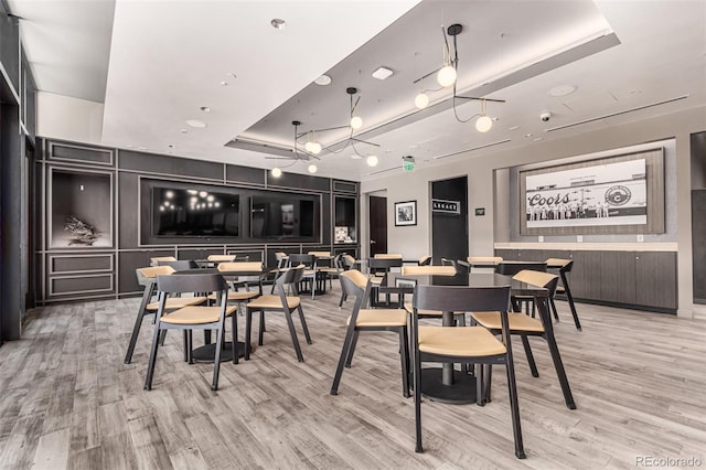 dining space featuring a raised ceiling and light wood-type flooring