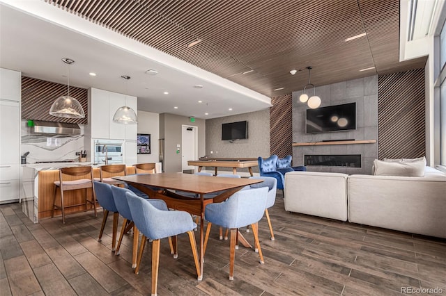 dining area with a tiled fireplace and dark wood-type flooring