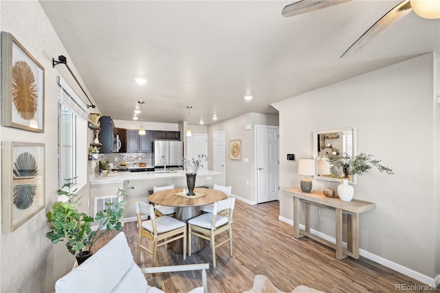 dining area featuring wood-type flooring, sink, and a textured ceiling