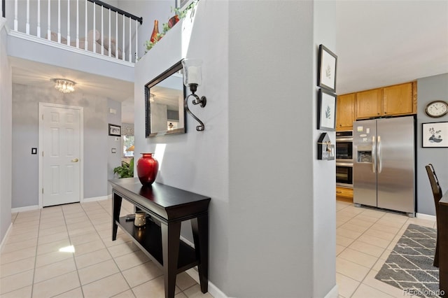 hall featuring baseboards and light tile patterned flooring