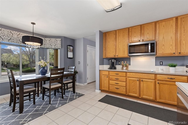 kitchen with light countertops, light tile patterned floors, stainless steel microwave, black electric stovetop, and a chandelier