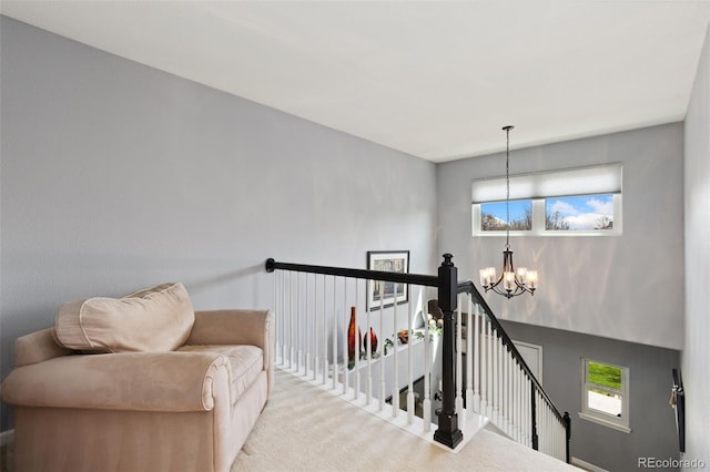interior space with carpet flooring, a chandelier, and an upstairs landing