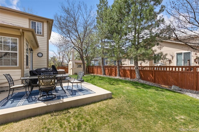 view of yard featuring a patio, a fenced backyard, a storage unit, an outbuilding, and outdoor dining space