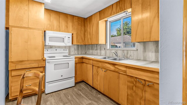 kitchen featuring light wood-type flooring, backsplash, sink, and white appliances