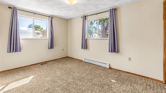 empty room featuring carpet flooring, a baseboard heating unit, and a wealth of natural light