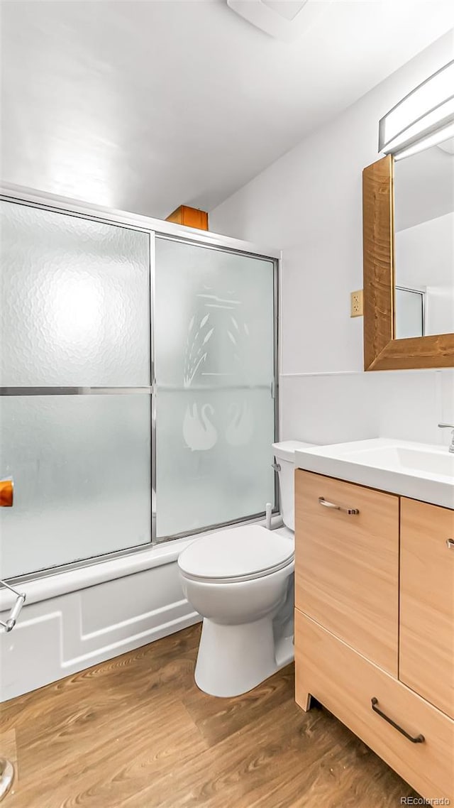 full bathroom featuring enclosed tub / shower combo, wood-type flooring, vanity, and toilet