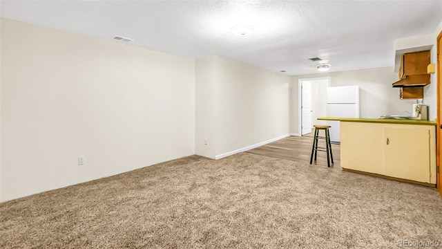 interior space with a kitchen breakfast bar, white refrigerator, and carpet flooring