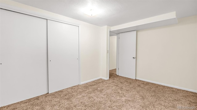 unfurnished bedroom with light carpet, a closet, and a textured ceiling