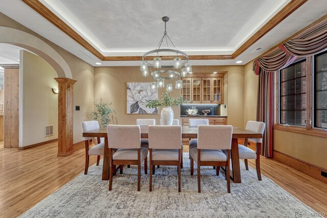 14581 E Oberlin Pl, Aurora, CO 80014 - dining area featuring arched walkways, a tray ceiling, light wood-type flooring, a chandelier, and baseboards