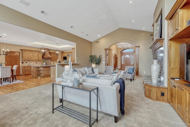 14581 E Oberlin Pl, Aurora, CO 80014 - living area with arched walkways, light colored carpet, a chandelier, recessed lighting, and lofted ceiling