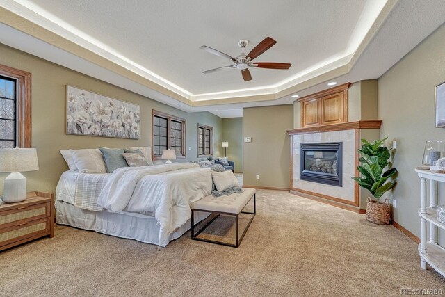 14581 E Oberlin Pl, Aurora, CO 80014 - carpeted bedroom featuring a tray ceiling, a tile fireplace, baseboards, and a ceiling fan