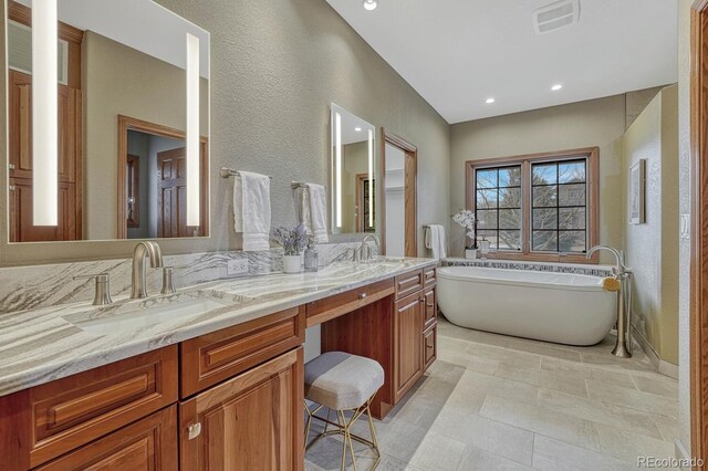 14581 E Oberlin Pl, Aurora, CO 80014 - full bath featuring double vanity, a freestanding tub, a textured wall, and recessed lighting