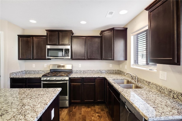 10733 Calista Way, Fountain, CO 80817 - kitchen featuring appliances with stainless steel finishes, a sink, dark wood finished floors, dark brown cabinetry, and light stone countertops
