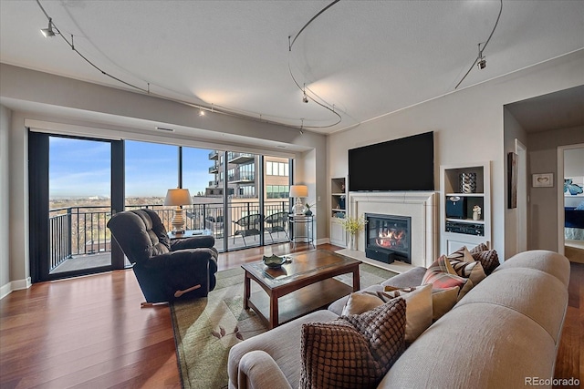 living room featuring wood-type flooring, a textured ceiling, track lighting, and a wealth of natural light